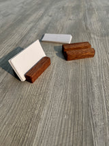 A set of dark brown wooden desk accessories, including two small rectangular blocks and a white card holder with blank white cards, arranged on a gray wood-grain surface.