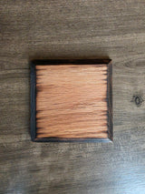 The back of an oak wood coaster with burnt, chamfered edges.
