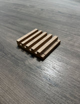 A small rectangular soap dish, shown on a dark wood-grain surface.
